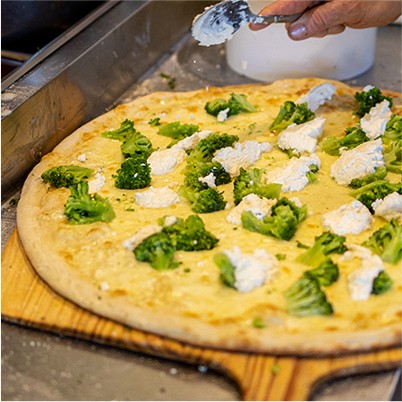 large white pizza with ricotta cheese and broccoli